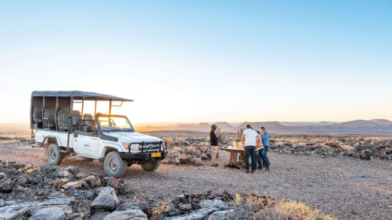 People standing around a bench while on a tour near the Fish River Lodge.
